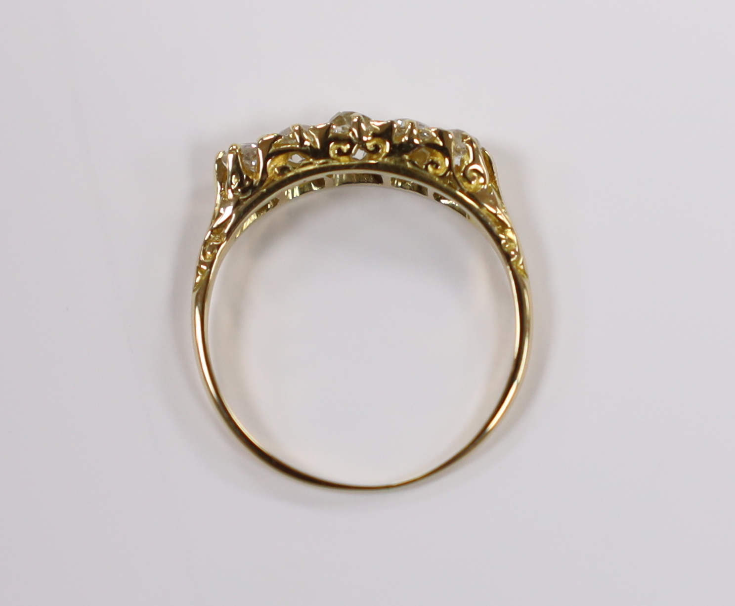 An early 20th century yellow metal and graduated five stone old round diamond set half hoop ring, size M, gross weight 2 grams.